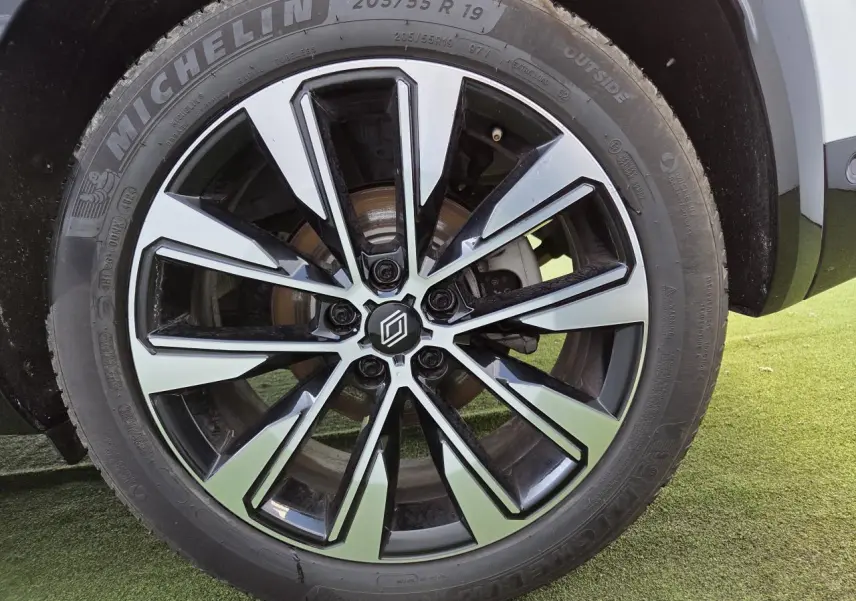 Gros plan sur la jante alliage 19 pouces diamantée noire du Renault Austral blanc nacré, avec pneu Michelin visible.