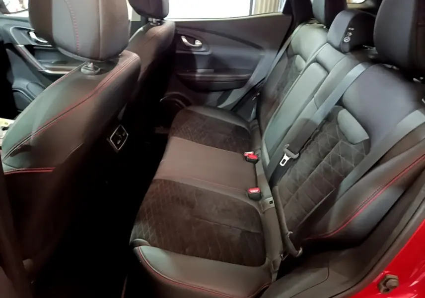 Vue intérieure arrière droite du Renault Kadjar rouge, sièges en cuir noir avec surpiqûres rouges et ceinture de sécurité visible.