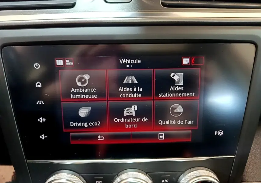 Écran tactile central du tableau de bord du Renault Kadjar rouge, affichant les options d’aides à la conduite et stationnement.