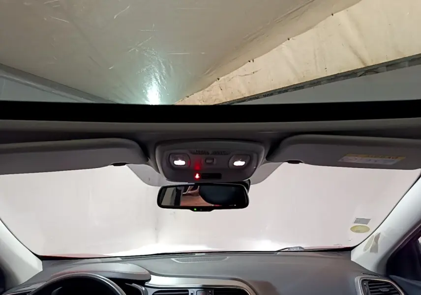 Vue intérieure frontale du tableau de bord et du rétroviseur d’un Renault Kadjar rouge avec toit ouvrant panoramique.
