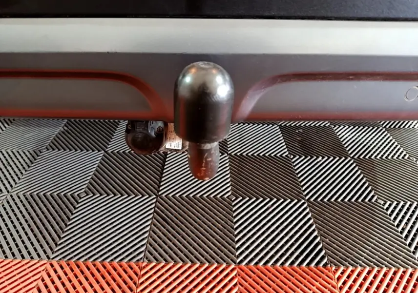 Gros plan sur l'attelage noir sous le pare-chocs arrière du Renault Kadjar rouge, posé sur un sol à damiers noir et rouge.