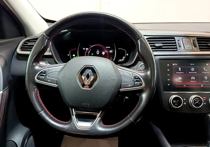 Vue intérieure centrée sur le volant cuir noir avec surpiqûres rouges et tableau de bord numérique du Renault Kadjar 2019.