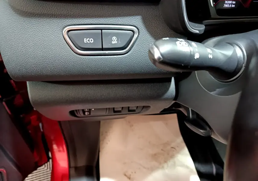 Détail intérieur côté gauche du tableau de bord du Renault Kadjar rouge, avec boutons ECO et commande au volant visible.