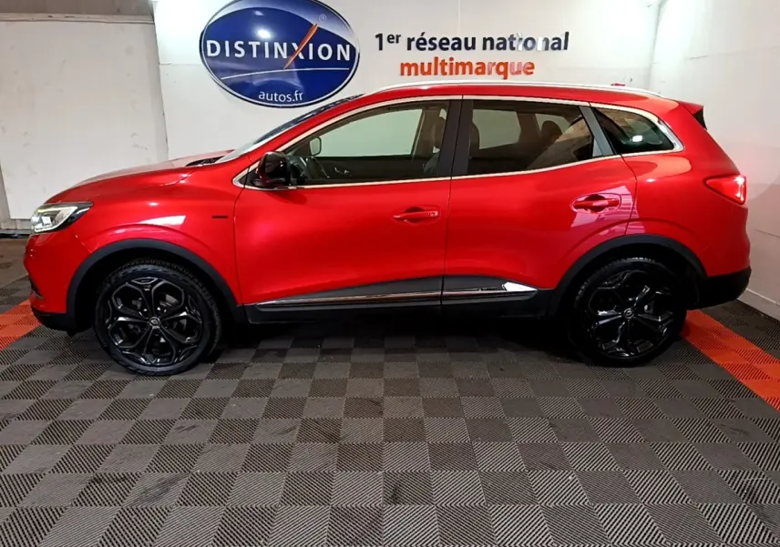 Vue de profil côté gauche d'un Renault Kadjar rouge SL Black Edition avec jantes noires brillantes en intérieur showroom.