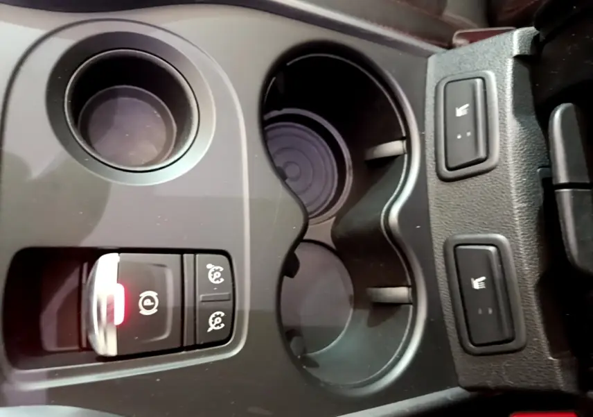 Gros plan sur la console centrale noire du Renault Kadjar rouge, avec porte-gobelets et boutons de sièges chauffants.