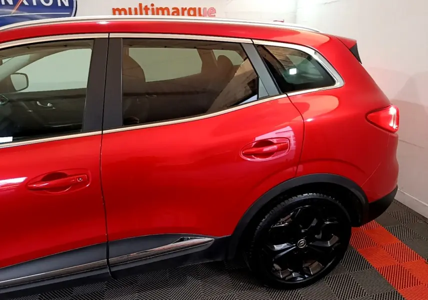 Vue côté droit arrière du Renault Kadjar SL Black Edition rouge avec jantes noires brillantes et poignées de porte ton caisse.