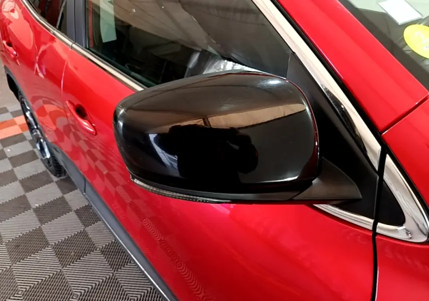 Rétroviseur noir en gros plan côté gauche sur Renault Kadjar SL Black Edition rouge vue partielle côté avant.