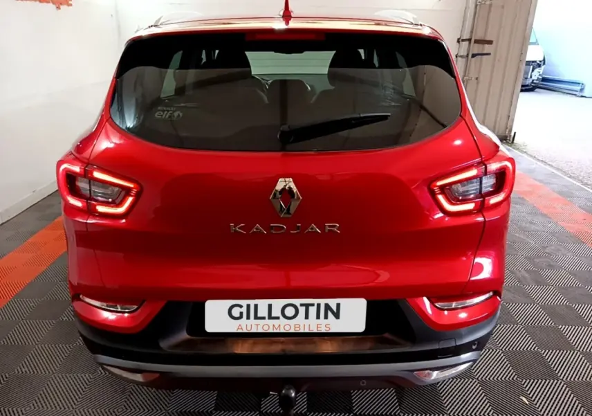 Vue arrière d’un Renault Kadjar rouge avec feux LED et logo central, stationné en intérieur sur sol damier.