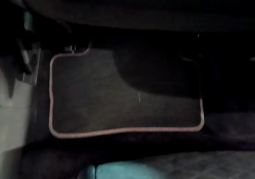 Tapis de sol noir avec bordure beige dans l'habitacle d'un Renault Kadjar rouge, vue côté conducteur.