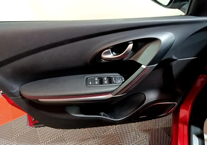 Vue rapprochée de la porte avant gauche rouge du Renault Kadjar SL Black Edition avec commandes de vitres et poignée chrome.