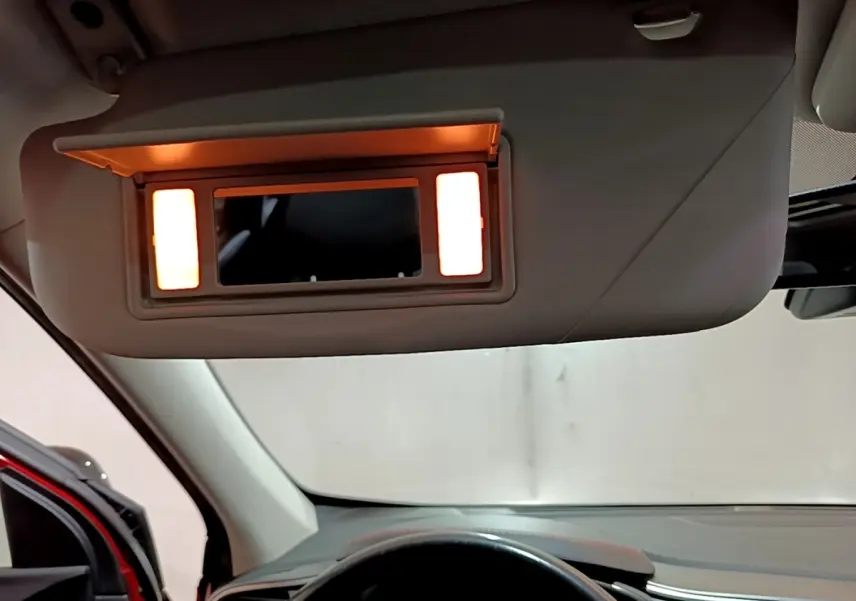 Vue intérieure du pare-soleil avec miroir éclairé du Renault Kadjar rouge, côté conducteur, tableau de bord visible.