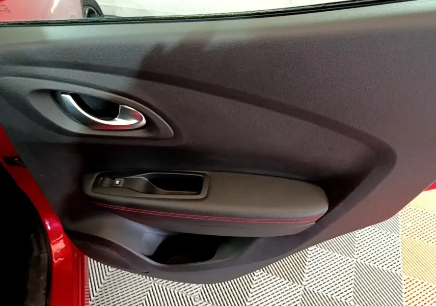 Vue rapprochée de la porte intérieure côté gauche rouge du Renault Kadjar avec poignée argentée et surpiqûres rouges.