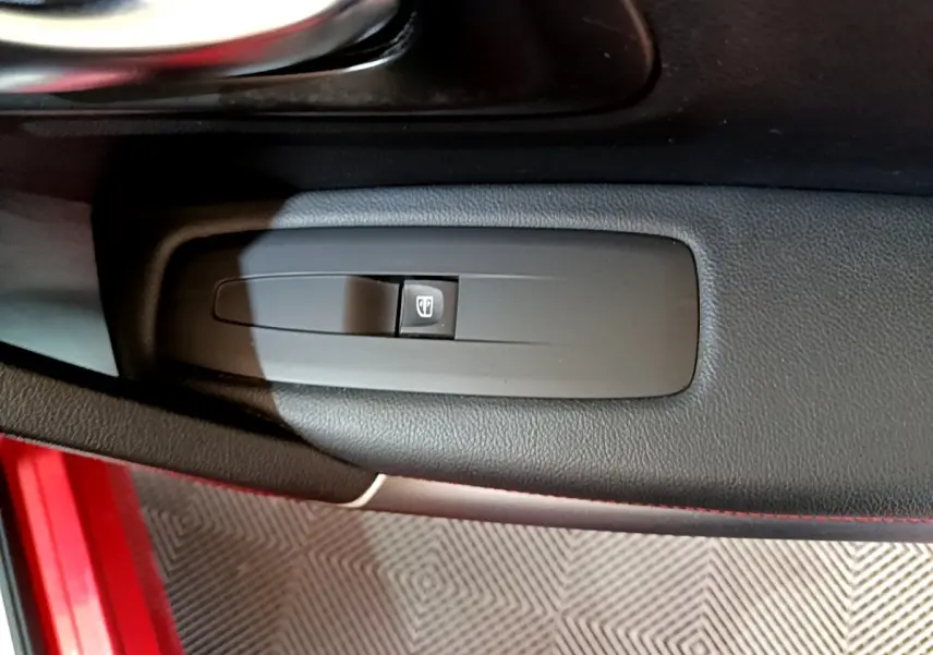 Gros plan sur le bouton de commande de la vitre électrique côté conducteur du Renault Kadjar rouge, intérieur noir.