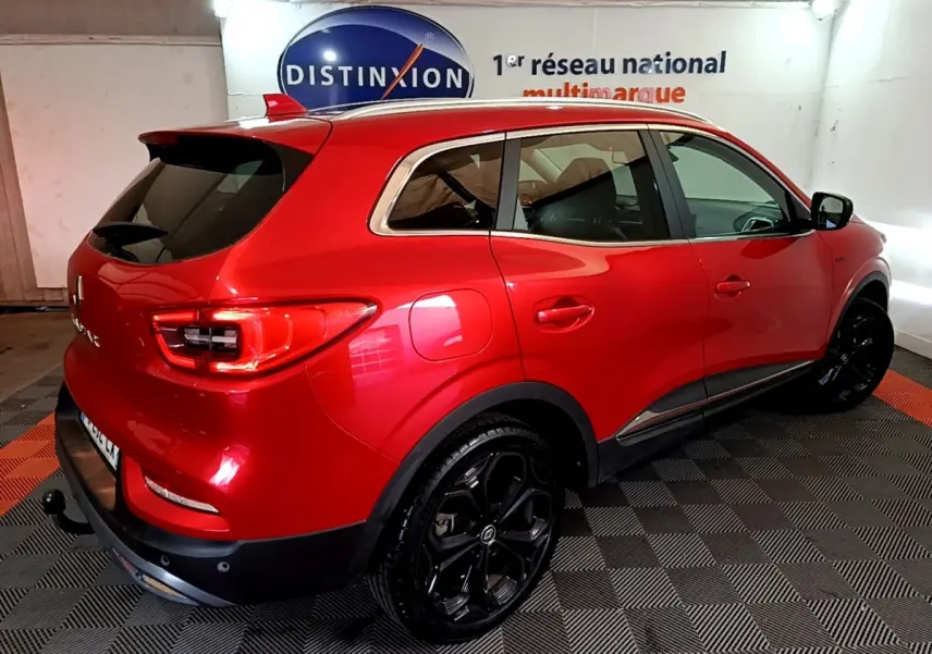 Vue 3/4 arrière droite du Renault Kadjar SL Black Edition rouge avec jantes noires et vitres teintées en intérieur showroom.