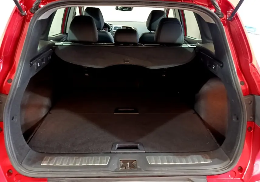 Vue arrière du coffre ouvert du Renault Kadjar rouge, montrant l'espace de chargement et la banquette arrière noire.