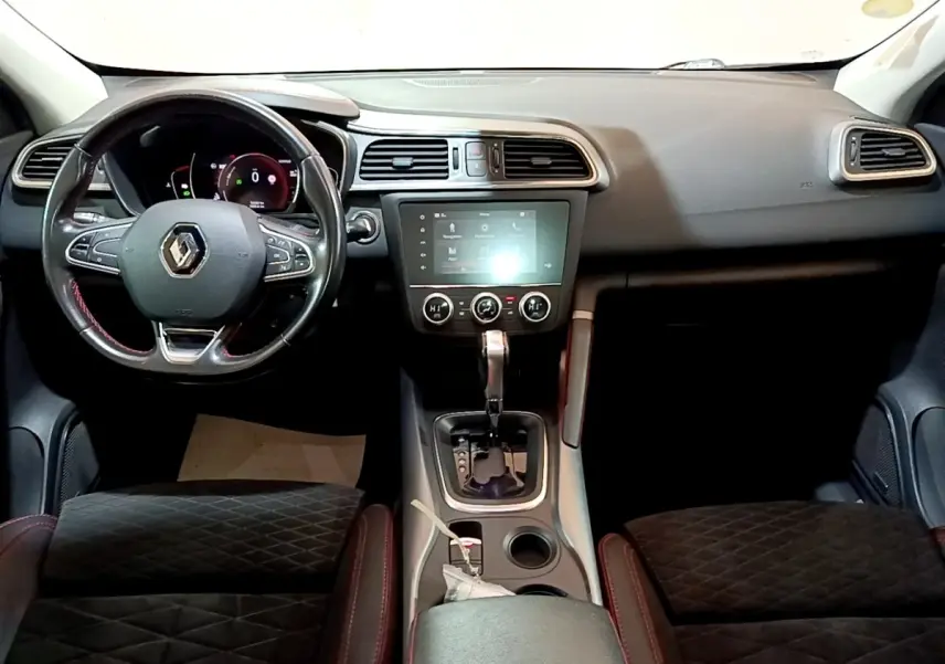 Vue intérieure avant du Renault Kadjar SL Black Edition avec tableau de bord noir, volant cuir et écran tactile central allumé.