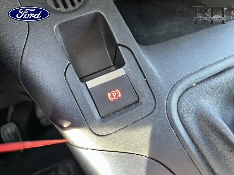 Gros plan sur le bouton de frein de stationnement électrique rouge dans l'habitacle du Peugeot Rifter blanc, version 2020.