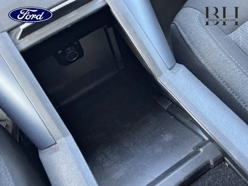 Vue intérieure en gros plan du rangement central noir et tissu gris du siège avant droit du Peugeot Rifter blanc.