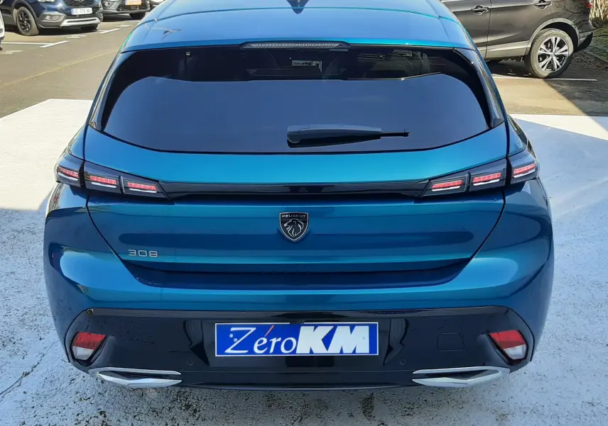 Vue arrière d'une Peugeot 308 Bleu Obsession 2025 avec feux LED et double sortie d'échappement chromée sur parking.