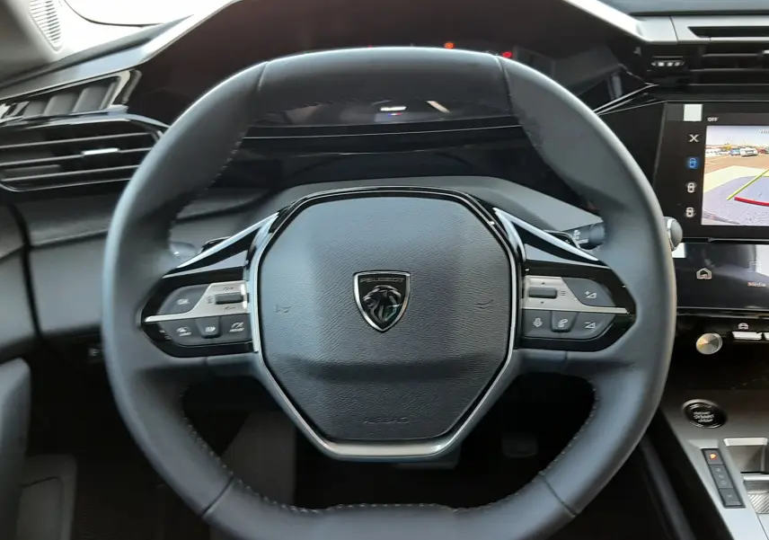 Vue centrée sur le volant noir de la Peugeot 308 2025 avec écran tactile affichant la caméra 360° à droite.