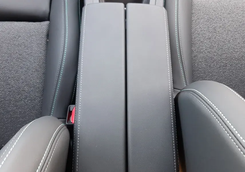 Vue plongeante sur l'accoudoir central en cuir noir avec surpiqûres blanches de la Peugeot 308 Bleu Obsession 2025.