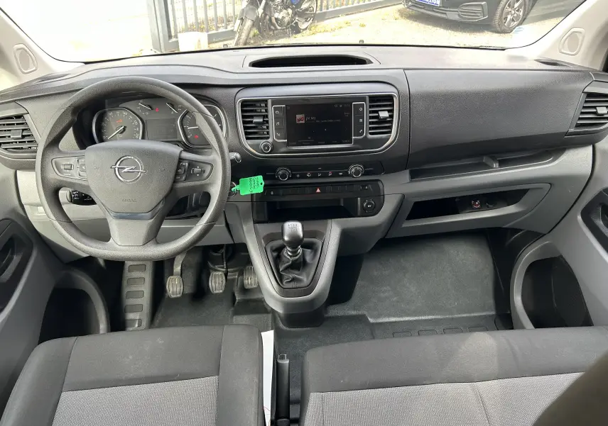 Vue intérieure avant de l'Opel Vivaro Combi 2022 avec tableau de bord noir et volant multifonction.