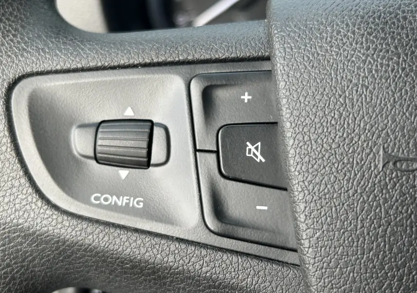 Gros plan sur les commandes de configuration et volume sur le volant noir de l'Opel Vivaro Combi 2022.