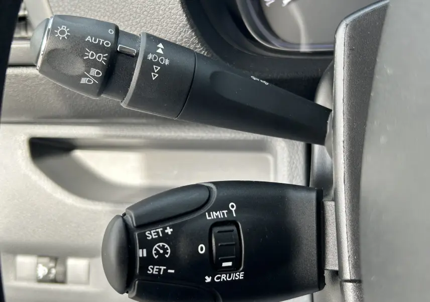 Gros plan sur les commandes de régulateur de vitesse et des feux sur la colonne de direction d’un Opel Vivaro Combi noir.