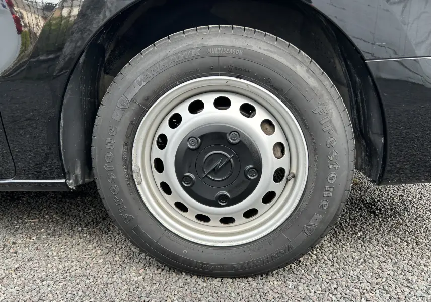 Gros plan sur la roue avant gauche noire d’un Opel Vivaro Combi 2022 avec jante acier et pneu Firestone.