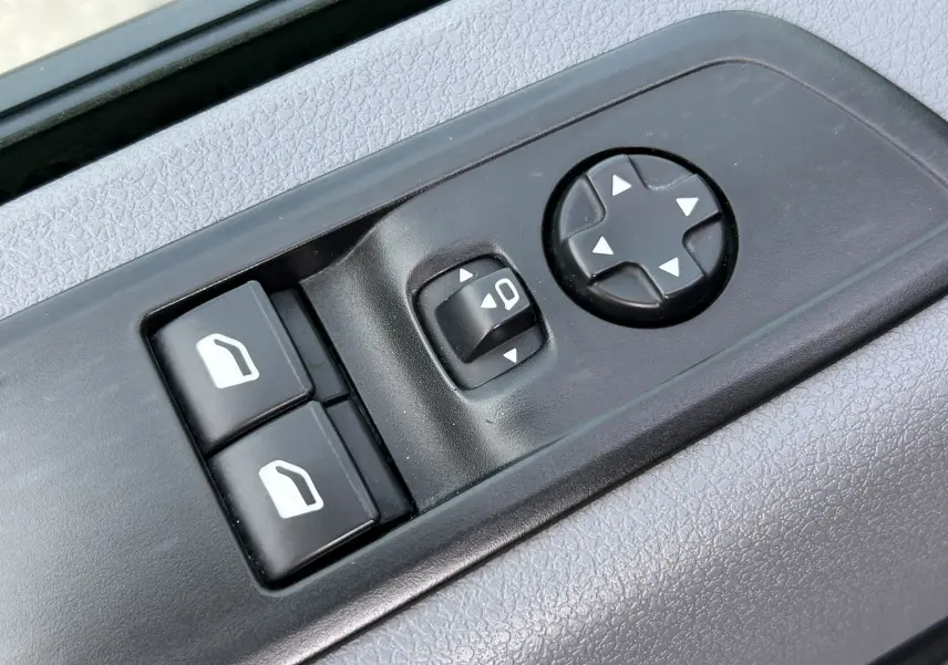 Gros plan sur les commandes de réglage des vitres et des rétroviseurs côté conducteur d’un Opel Vivaro Combi noir.