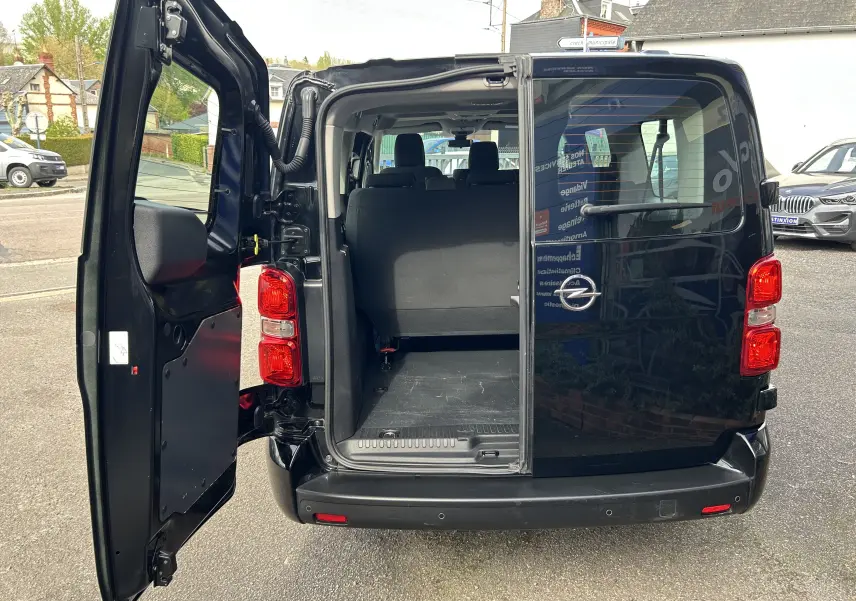 Vue arrière d'un Opel Vivaro Combi noir 2022 avec porte battante gauche ouverte montrant l'espace de chargement.
