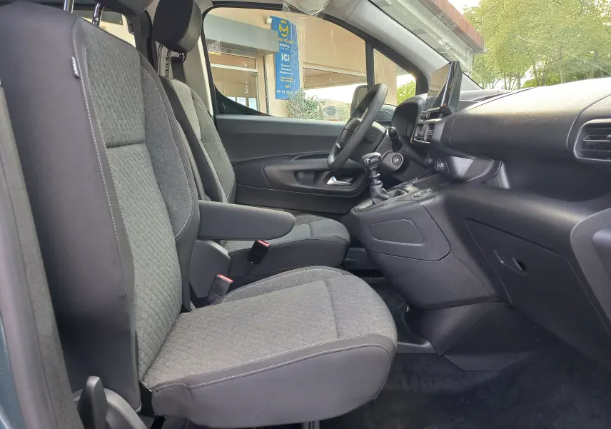 Vue intérieure côté gauche de l'Opel Combo Life 2025, montrant les sièges avant gris et le tableau de bord avec écran tactile.