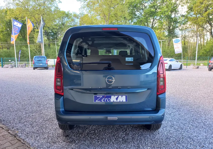 Vue arrière d’un Opel Combo Life bleu Kiama 2025 avec hayon vitré et feux arrière verticaux, stationné sur un parking.