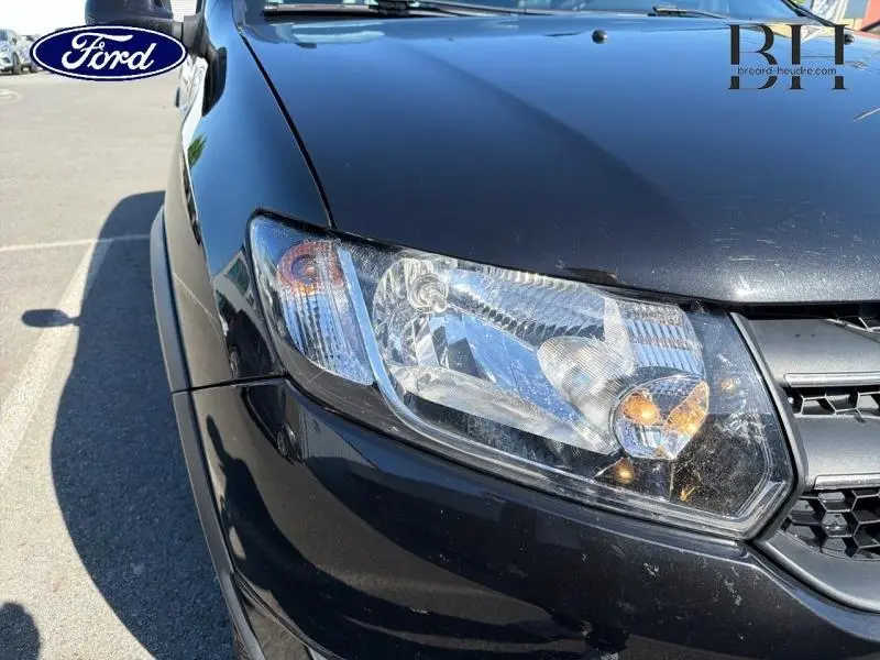 Gros plan sur le phare avant gauche d'une Dacia Sandero Stepway noir nacré, avec partie de la calandre visible.