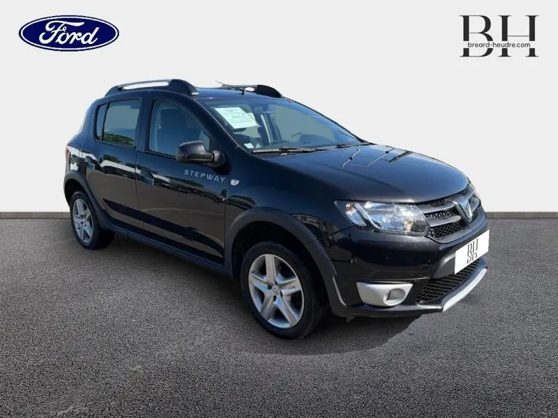 Dacia Sandero Stepway noir nacré vue 3/4 avant droit avec barres de toit et jantes alliage.