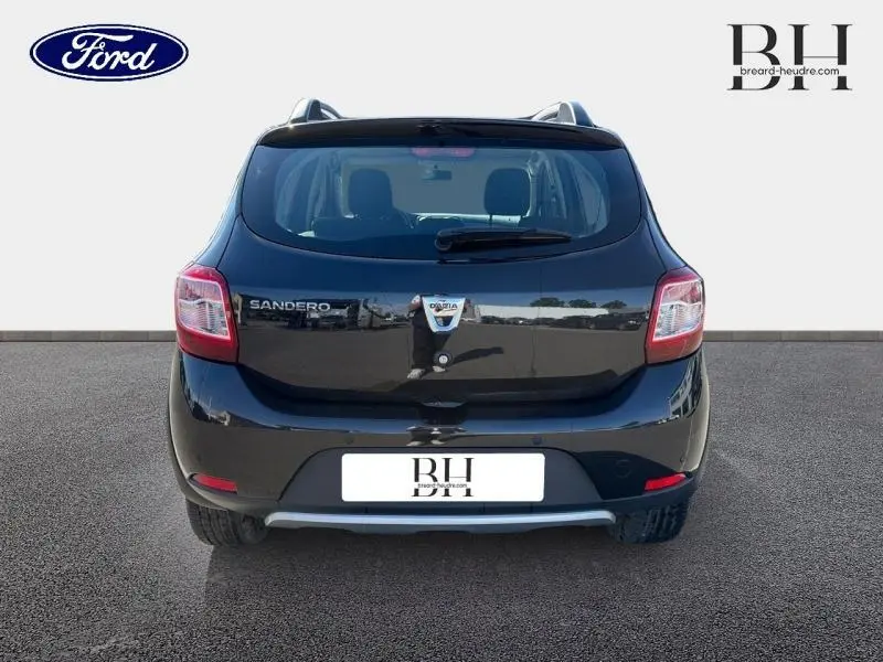 Vue arrière d'une Dacia Sandero Stepway noir nacré de 2016 avec barres de toit et feux arrière visibles.