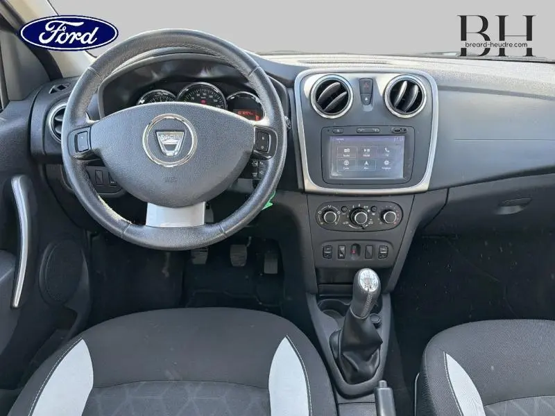 Vue intérieure avant de la Dacia Sandero noire nacrée 2016, volant cuir multifonction et écran tactile central.