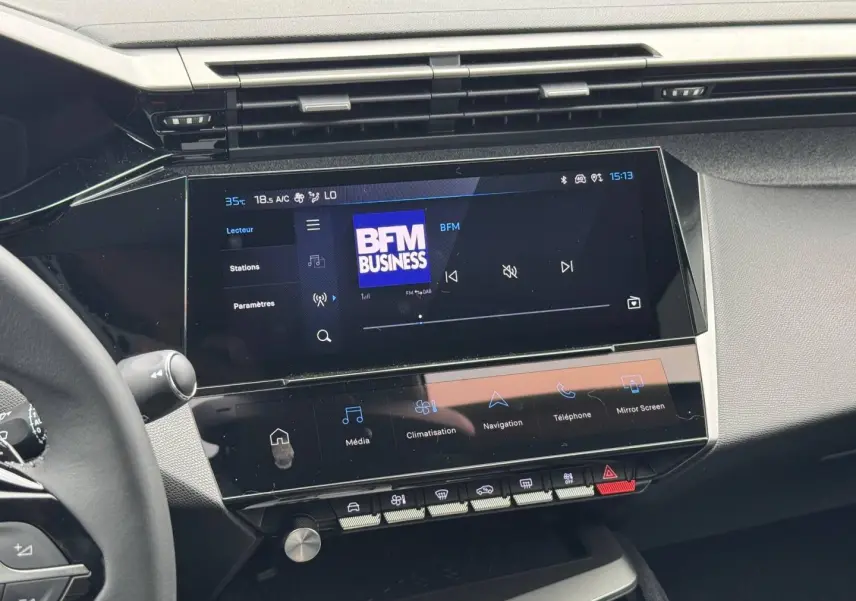 Vue intérieure du tableau de bord de la Peugeot 308 Hybrid 2025, écran tactile multifonction affichant BFM Business.