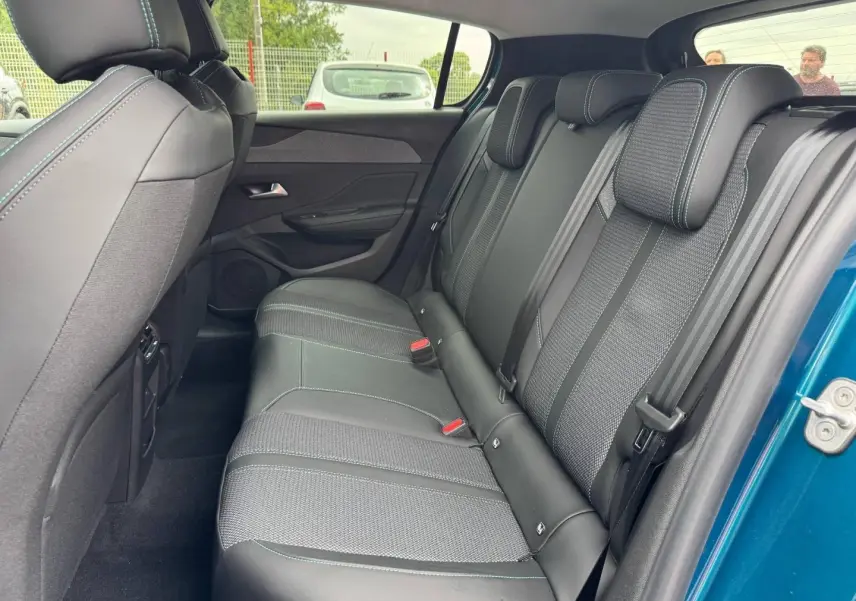 Vue latérale droite de la banquette arrière en tissu et cuir noir du Peugeot 308 bleu 2025, avec ceintures et appuie-têtes.