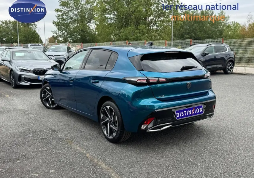 Vue 3/4 arrière droite d'une Peugeot 308 bleu Obsession avec feux arrière LED et jantes alliage modernes.