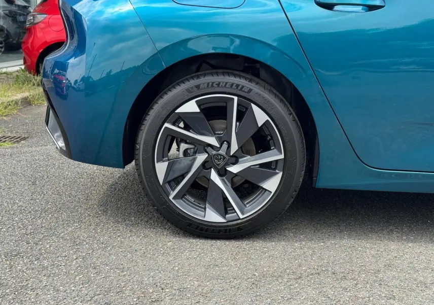 Gros plan sur la roue arrière gauche d'une Peugeot 308 bleu Obsession 2025 avec jante alu au design moderne.