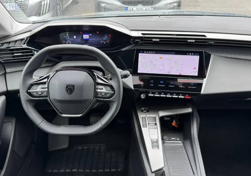 Vue intérieure centrée sur le volant et l’écran tactile du tableau de bord de la Peugeot 308 1.2 Hybrid 2025.