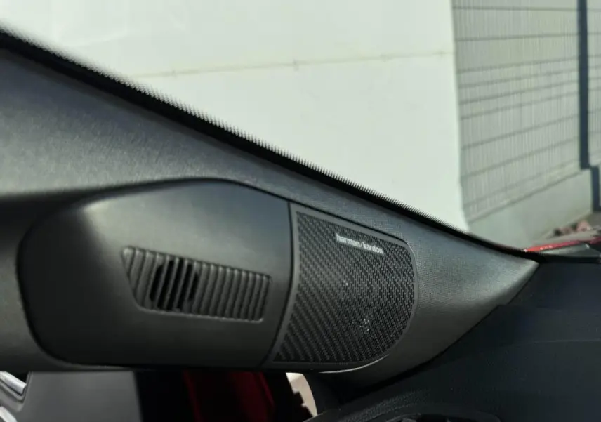Gros plan sur l'enceinte Harman Kardon côté passager d'un Renault Captur II rouge flamme toit noir.