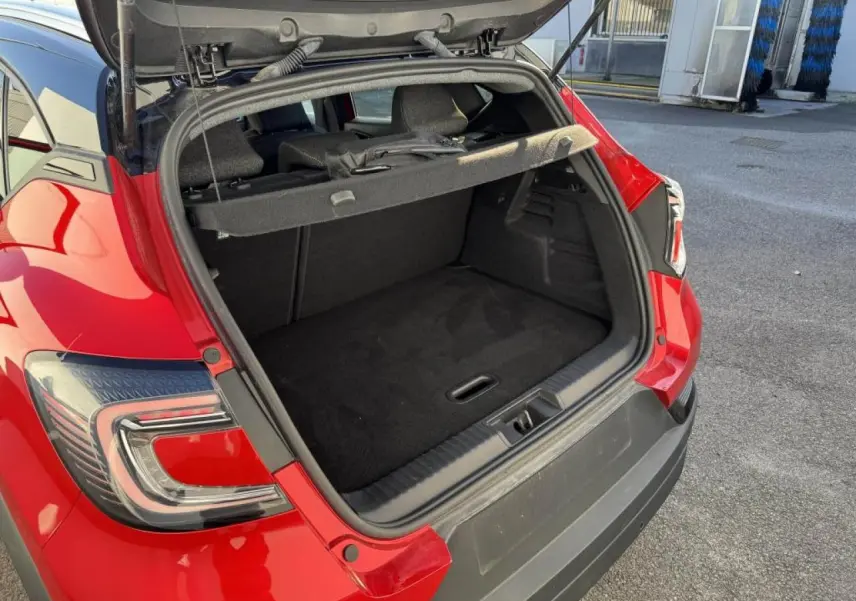 Coffre ouvert vu de l'arrière droit d'un Renault Captur II rouge flamme avec toit noir et feux arrière LED distinctifs.