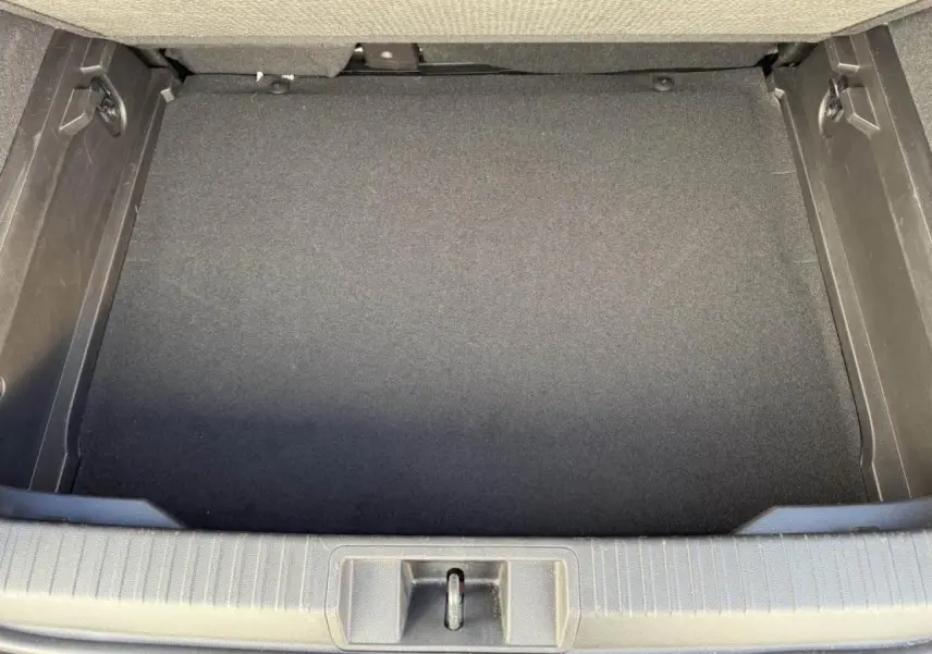 Coffre arrière vide du Renault Captur II 2025, vue plongeante montrant le plancher de coffre mobile en tissu noir.