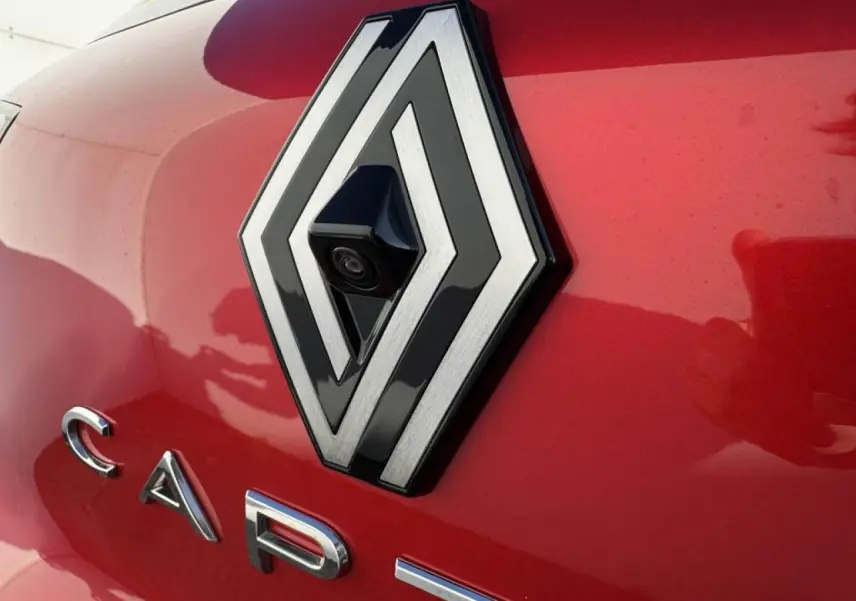 Gros plan sur le logo Renault avec caméra 360° intégrée sur la malle arrière rouge flamme du Captur II.