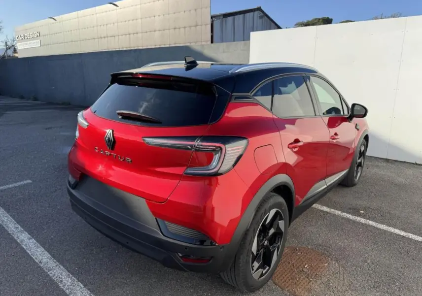 Vue 3/4 arrière droite du Renault Captur II rouge flamme avec toit noir étoilé et jantes aluminium noires.