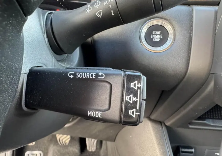 Gros plan sur la commande au volant et bouton Start Engine Stop du Renault Captur II rouge flamme avec intérieur noir.