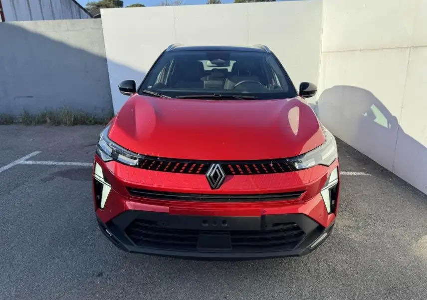 Vue frontale du Renault Captur II rouge flamme avec toit noir, mettant en valeur la calandre et les phares LED distinctifs.