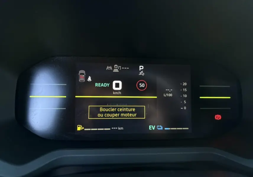 Tableau de bord digital du Dacia Duster gris, affichant la vitesse à 0 km/h et un message de sécurité ceinture.